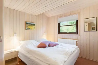 a bedroom with a white bed with two pillows on it at JB245-Fjerritslev-Tyttebaerstien-44 in Fjerritslev