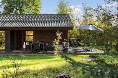 a cabin with a table and chairs and an umbrella at JB245-Fjerritslev-Tyttebaerstien-44 in Fjerritslev