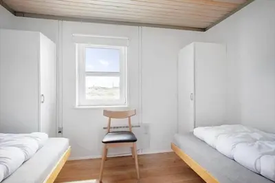 a room with two beds and a chair next to a window at JB109-Frostrup-Strandkaervej-8 in Frøstrup