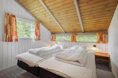 two beds in a room with wooden ceilings and windows at JB329-Brovst-Egernvej-29 in Brovst