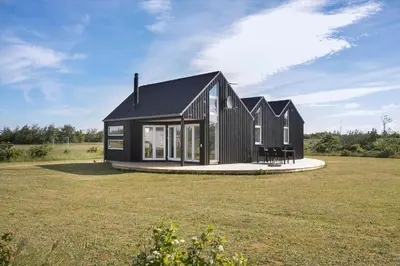 a black house in a field with a large yard at JB176-Brovst-Kronvildtvej-152 in Brovst