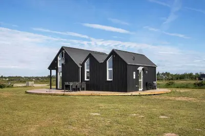a black house sitting on top of a grass field at JB176-Brovst-Kronvildtvej-152 in Brovst
