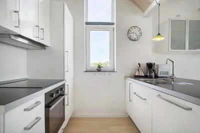 a kitchen with white cabinets and a clock on the wall at JB176-Brovst-Kronvildtvej-152 in Brovst