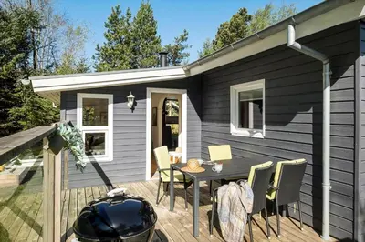 a black house with a table and chairs on a deck at JB246-Brovst-Graevlingevej-13 in Brovst