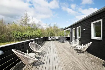 a deck with chairs and tables on a house at JB876-Brovst-Kronvildtvej-40 in Brovst