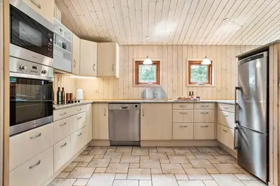a kitchen with wooden cabinets and stainless steel appliances at JB126-Fjerritslev-Tyttebaerstien-48 in Fjerritslev