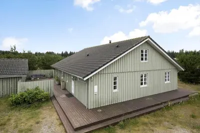 a small green house with a wooden deck at JB175-23-Brovst-Kronvildtvej-60 in Brovst