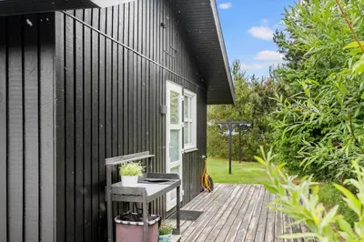 a black house with a wooden deck with a grill at JB318-Fjerritslev-Fiskerstien-10 in Fjerritslev