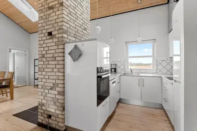 a kitchen with white cabinets and a brick wall at JB187-Brovst-Kronvildtvej-128 in Brovst