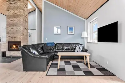 a living room with a black leather couch and a table at JB187-Brovst-Kronvildtvej-128 in Brovst