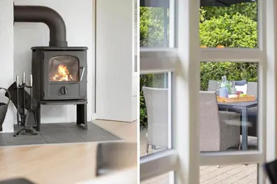 a wood stove in a living room with a table at JB716-Fjerritslev-Tyttebaerstien-16 in Fjerritslev