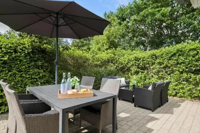 a table and chairs with an umbrella on a patio at JB716-Fjerritslev-Tyttebaerstien-16 in Fjerritslev