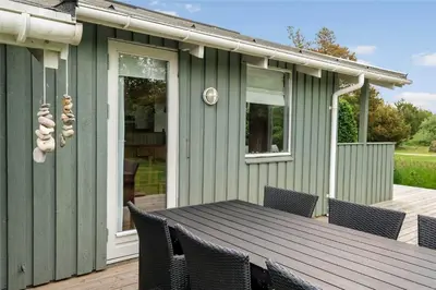 a green house with a table and chairs on a deck at JB122-Fjerritslev-Tyttebaerstien-14 in Fjerritslev