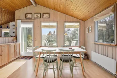 a kitchen with a table and chairs and windows at JB122-Fjerritslev-Tyttebaerstien-14 in Fjerritslev