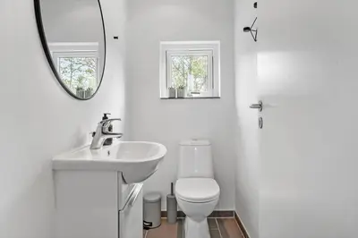 a bathroom with a sink and a toilet and a mirror at JB161-Brovst-Kronvildtvej-206 in Brovst