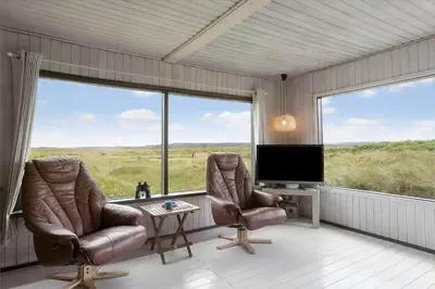 two chairs and a television in a room with large windows at JB233-Brovst-Ejstrup-Strandvej-24 in Brovst