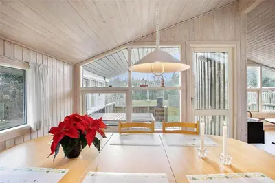 a dining room with a table with red flowers on it at JB137-Fjerritslev-Markstien-15 in Fjerritslev