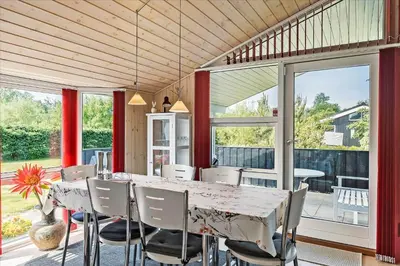 a dining room with a table and chairs and windows at JB166-Fjerritslev-Egevej-26 in Fjerritslev