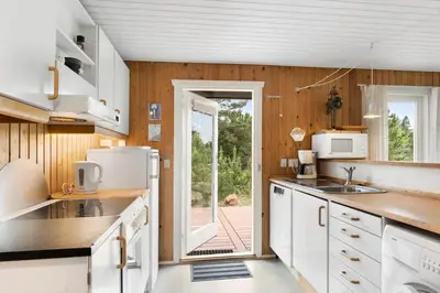 a kitchen with white appliances and a door to a yard at JB115-Fjerritslev-Blabaerstien-9 in Fjerritslev