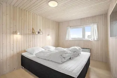 a bedroom with a bed with white sheets and a window at JB705-Frostrup-Svenstibakkevej-82 in Frøstrup