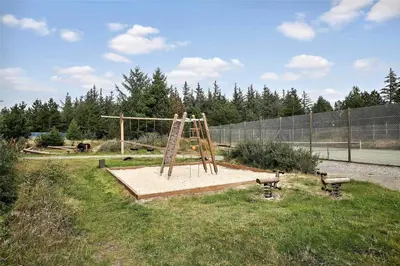 a playground with a wooden swing set in a field at JB158-Fjerritslev-Lynghojsletten-27 in Fjerritslev