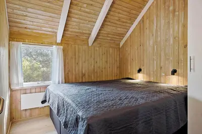 a bedroom with a bed in a room with wooden walls at JB628-Fjerritslev-Lynghojsletten-49 in Fjerritslev