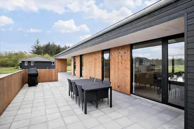 a patio with a black table and chairs on it at JB141-Brovst-Kronvildtvej-86 in Brovst
