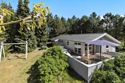 a white house with an umbrella on a yard at JB291-Fjerritslev-Stenhusvej-30 in Fjerritslev
