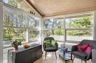 a screened in porch with two chairs and windows at JB255-Fjerritslev-Blabaerstien-22 in Fjerritslev
