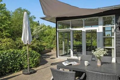 a patio with an umbrella and a table and chairs at JB231-Fjerritslev-Poppelvej-2 in Fjerritslev