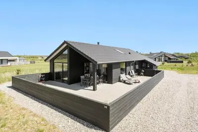 a black house with a large deck in a field at JB172-Brovst-Kronvildtvej-110 in Brovst