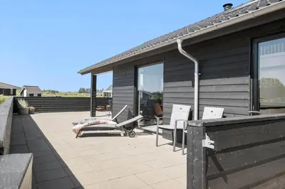 a patio with two chairs and a house with windows at JB172-Brovst-Kronvildtvej-110 in Brovst