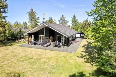 a black house with a deck in a yard at JB295-Brovst-Ildervej-7 in Brovst