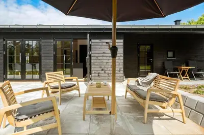 a patio with chairs and a table and an umbrella at JB330-Fjerritslev-Perikumvej-12 in Fjerritslev