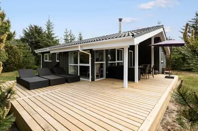 a wooden deck with a couch and an umbrella at JB260-Fjerritslev-Blabaerstien-76 in Fjerritslev