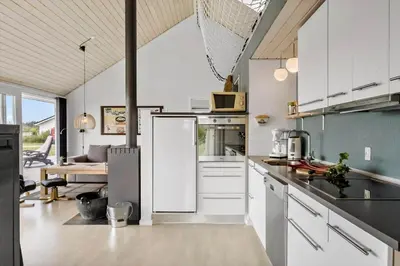 a kitchen with white cabinets and a living room at JB359-Brovst-Kronvildtvej-242 in Brovst