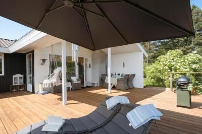 a patio with chairs and an umbrella on a deck at JB401-Brovst-Solsortevej-1 in Brovst
