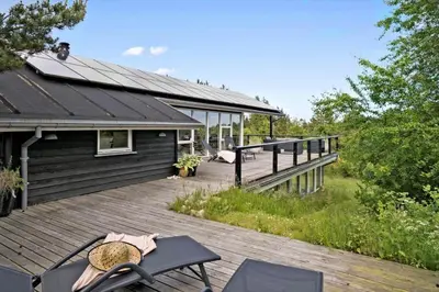 a wooden deck with chairs and a house at JB400-Brovst-Solsortevej-7 in Brovst