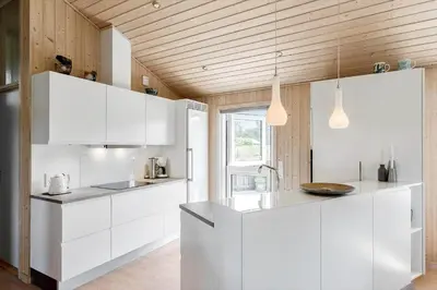 a kitchen with white cabinets and a wooden ceiling at LK1902-Lokken-Olgavej-40 in Løkken