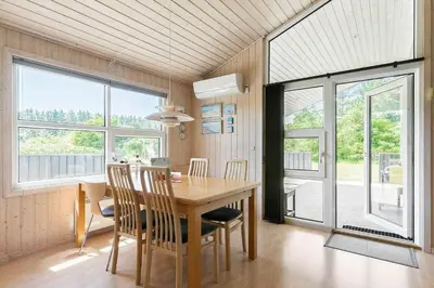 a dining room with a table and chairs and windows at LK1902-Lokken-Olgavej-40 in Løkken