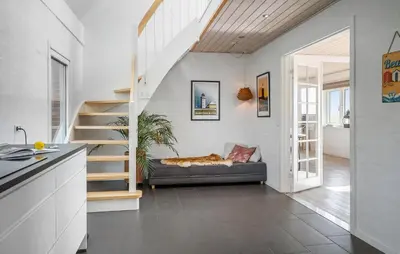 a living room with a staircase and a couch at 2 Bedroom Amazing Home In Thyholm in Thyholm