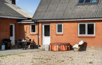 a red brick house with a wooden barrel in front of it at 2 Bedroom Amazing Home In Thyholm in Thyholm