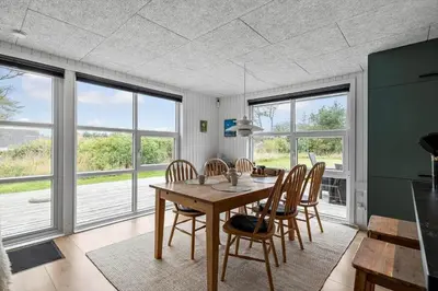 a dining room with a table and chairs and windows at LK2185-Lokken-Marthinesvej-17 in Løkken