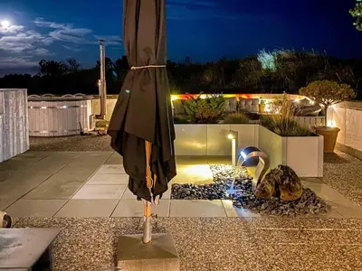 a closed umbrella sitting on a patio at night at Family-Friendly House with Sauna in Pandrup