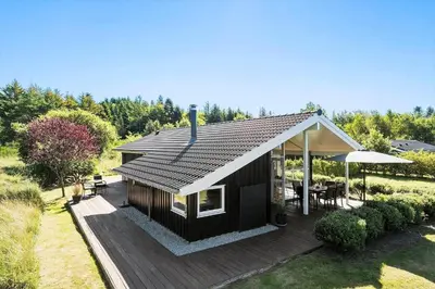 a black house with a deck and an umbrella at JB403-Fjerritslev-Poppelvej-20 in Fjerritslev
