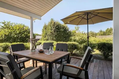 a wooden table with chairs and an umbrella on a deck at JB403-Fjerritslev-Poppelvej-20 in Fjerritslev
