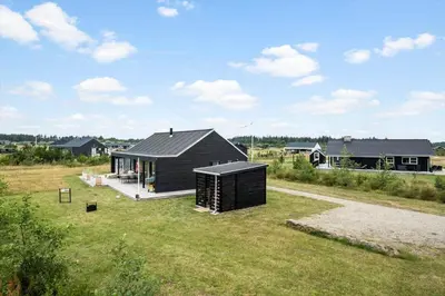 a small black house on a grass field at JB366-Brovst-Kronvildtvej-118 in Brovst