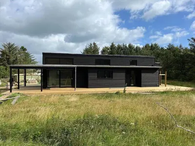 a large black house with glass windows in a field at JB365-Fjerritslev-Hedestien-9 in Fjerritslev