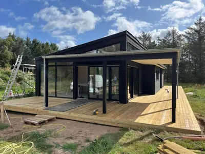 a small black house on a wooden deck at JB365-Fjerritslev-Hedestien-9 in Fjerritslev