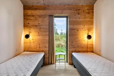 two beds in a room with a chair and a window at LK2174-Lokken-Stellavej-18 in Løkken